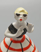 Фигурка «Сплетница в очках и полосатой юбке» (Склочница) из композиции «Разговор», скульпторы Дегтярев А. В.,​ Сморгон Л. Н., фарфор, ЛЗФИ, 1950-60 гг.